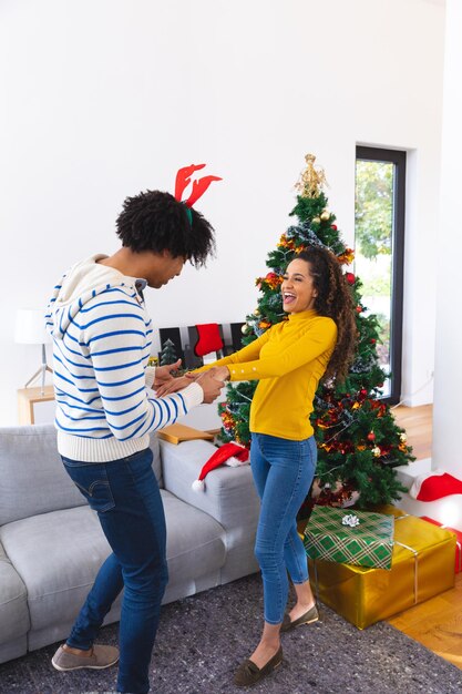 Photo happy african american couple dancing next to christmas tree. spending quality time at christmas together.