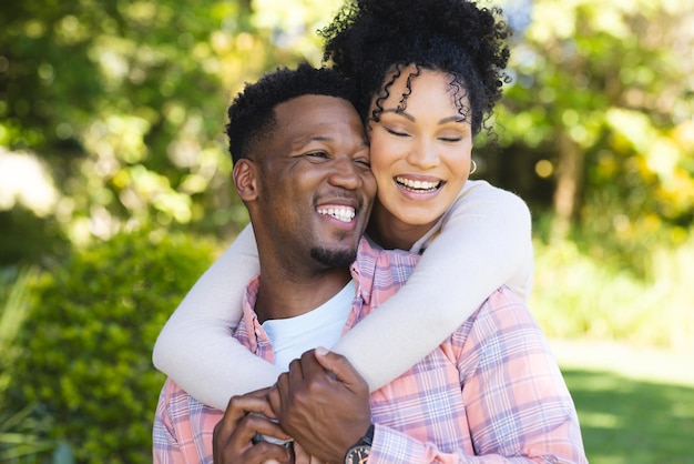 Happy african american couple embracing in sunny garden copy space