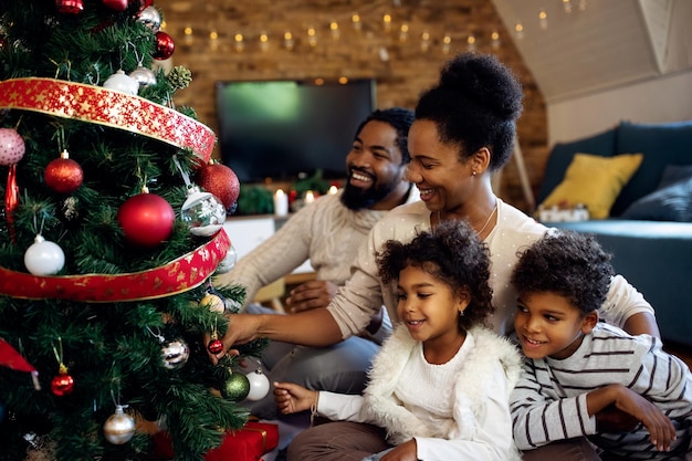 Happy African American family decorating Christmas tree at home