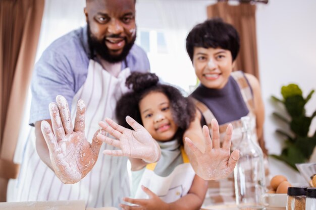 Happy African American family enjoy together while prepare the flour for making cookies at home Look at camera