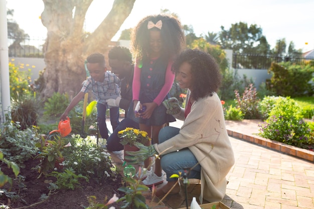 행복한 아프리카계 미국인 가족이 함께 꽃을 심고 식물에 물을 줍니다. 가족 시간, 집과 정원에서 함께 즐거운 시간을 보내십시오.