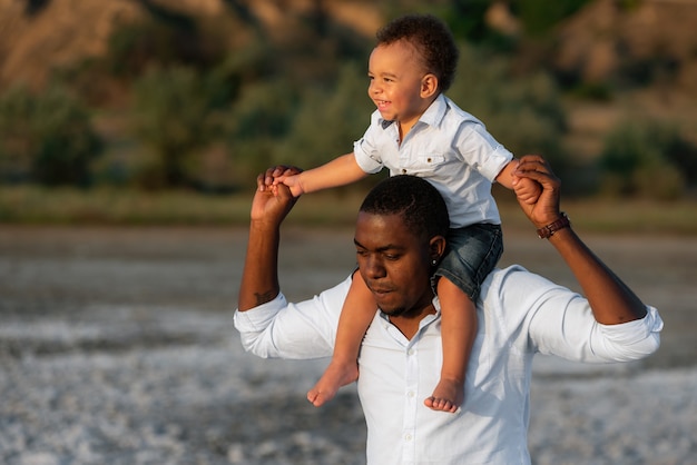 Cheerful african american father giving son piggyback ride outdoors  smiling, Happiness family concepts 6774671 Stock Photo at Vecteezy