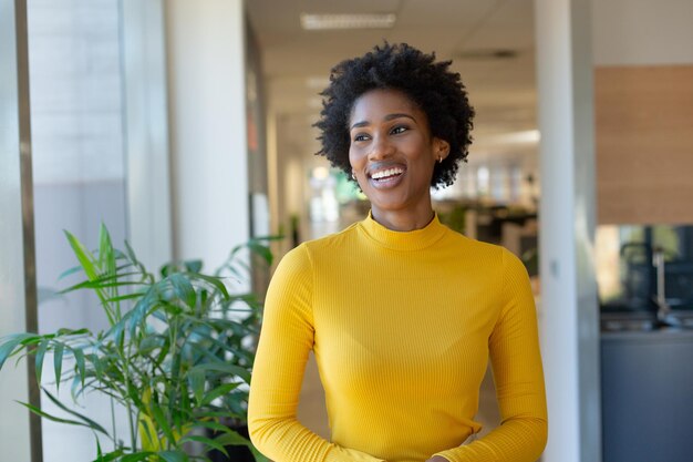 Happy african american female advisor with afro hairstyle looking away at modern workplace