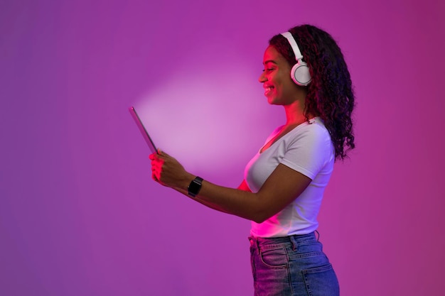 Happy African American Female Using Digital Tablet With Glowing Screen Side View