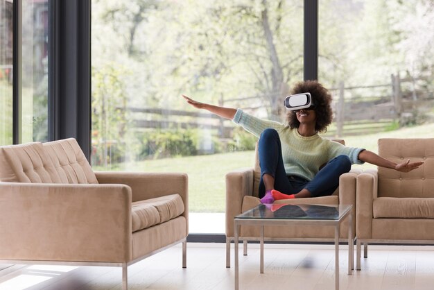 Happy african american girl getting experience using VR headset glasses of virtual reality at home