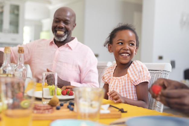 추수감사절에 행복한 아프리카계 미국인 소녀가 집에서 가족과 함께 점심을 먹고 있습니다. 변경되지 않은, 가족, 음식, 공생, 문화 및 휴일 개념.
