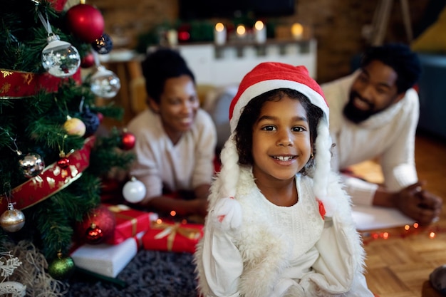 Happy African American girl wearing Santa hat at home on Christmas day