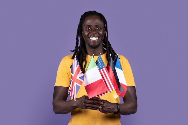 Happy african american guy holding diverse flags