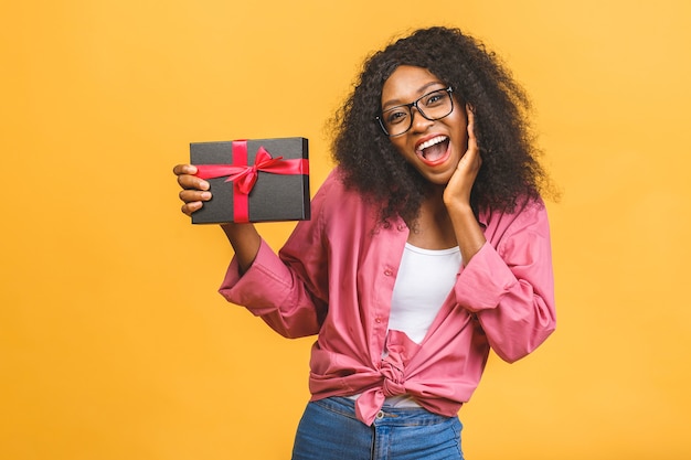 Happy african american lady in casual looking aside and laughing while holding present