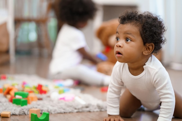 幸せなアフリカ系アメリカ人の小さな男の子が這って学びたいことを探しています