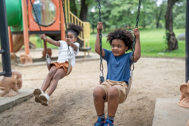 幸せなアフリカ系アメリカ人の小さな男の子と女の子は、公園の遊び場で楽しい時間を過ごします