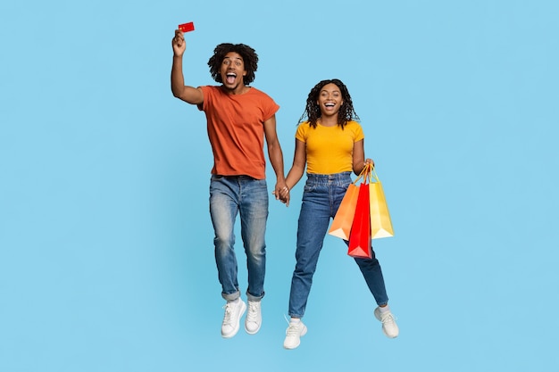 Happy african american lovers with shopping bags and credit card