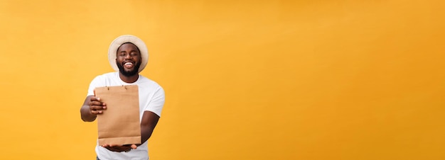 Happy african american man holding shopping bags on yellow background holidays concept