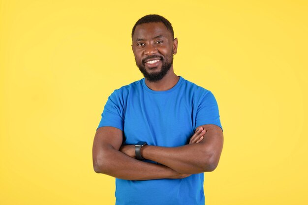 Счастливый афроамериканец позирует, улыбаясь, стоя на желтом фоне