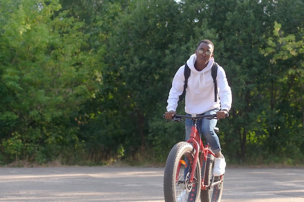 A happy African American man rides a bicycle through a public park Sports and recreation