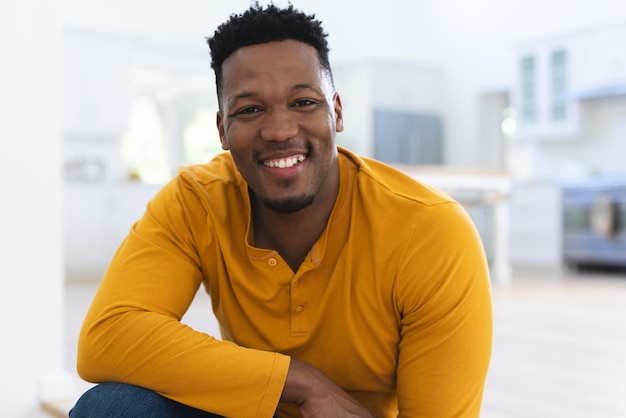 Happy african american man sitting on stairs at home copy space