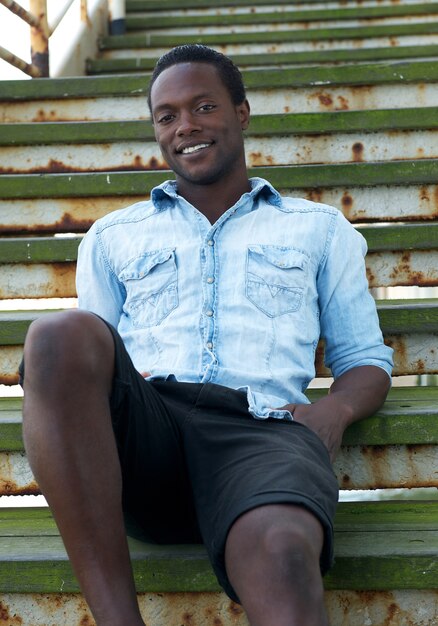 Photo happy african american man sitting on stairs outdoors