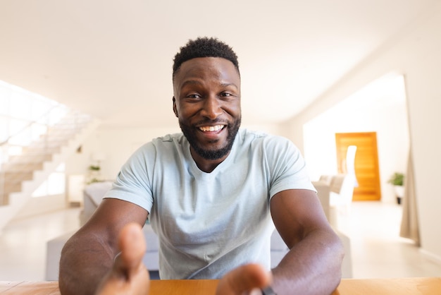 Happy african american man sitting at table and having video call. Spending quality time at home, domestic life and lifestyle concept.