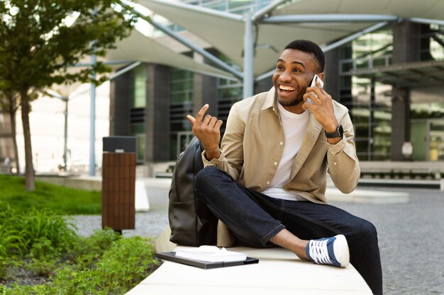 Uomo afroamericano felice che parla sul telefono cellulare e che gesturing