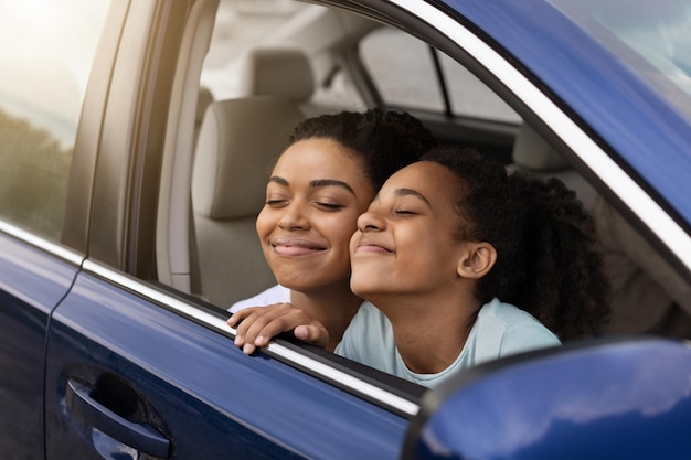 Happy african american mom and daughter sitting in car