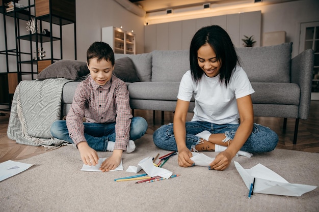 Happy african american mom teaching her sons to draw with pencils