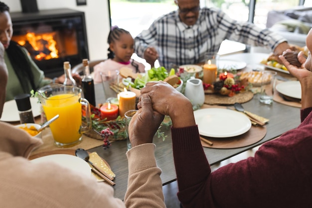 Photo happy african american multi generation family holding hands at thanksgiving dinner