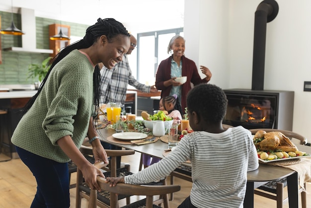 Happy african american multi generation family serving food at thanksgiving dinner