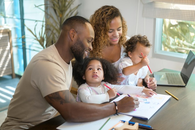 Happy African American parent playing and drawing with daughters in home