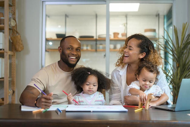 Happy African American parent playing and drawing with daughters in home