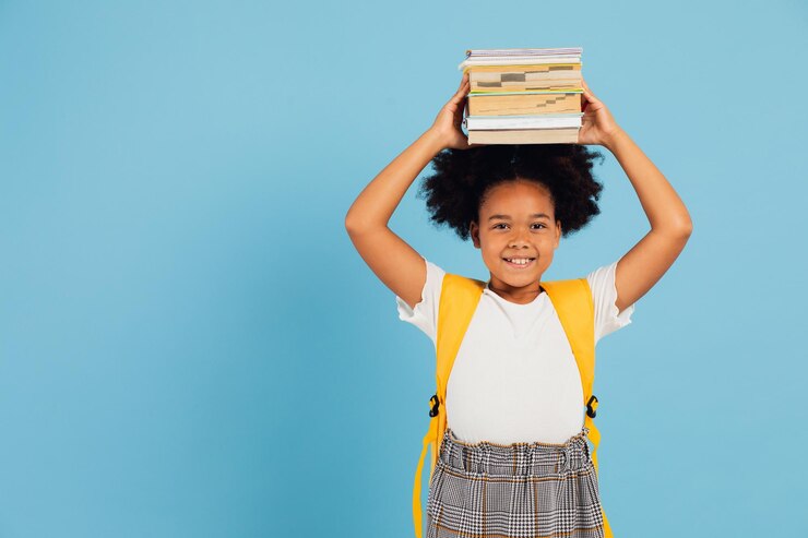 Photo happy african american schoolgirl holding books above head on blue background back to school concept