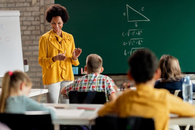 Happy African American teacher communicating with her students during a class