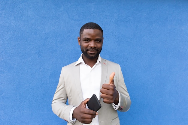 The happy African American with phone on blue background