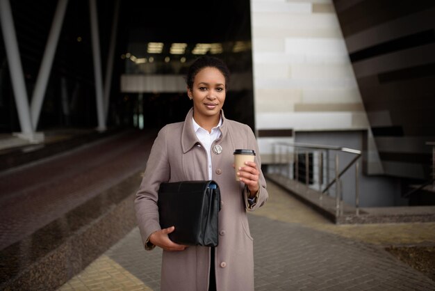 Happy african american woman in business clothes goes to a meeting in the office with a notepad and