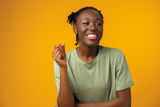 Happy african american woman looking surprised in yellow studio