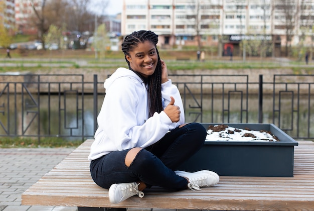 The happy African American woman in the Park on a bench