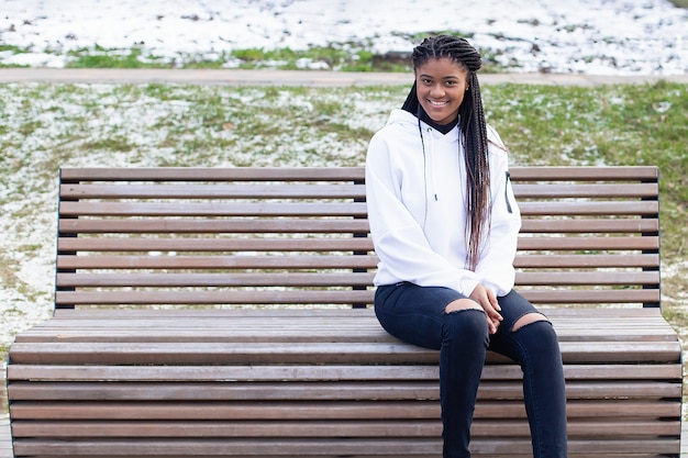 The happy African American woman in the Park on a bench