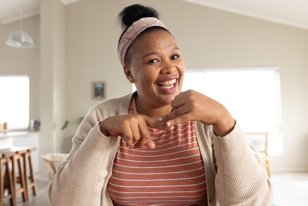 Happy african american woman sitting at table and having video call. Lifestyle, video call, communication and domestic life, unaltered.