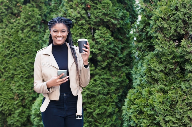 Happy african american woman on the street with coffee.