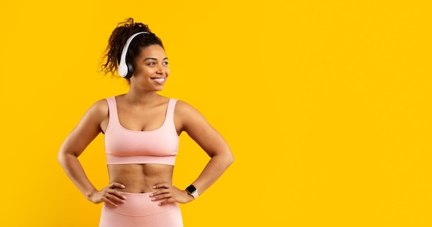 Happy african american woman with headphones on yellow