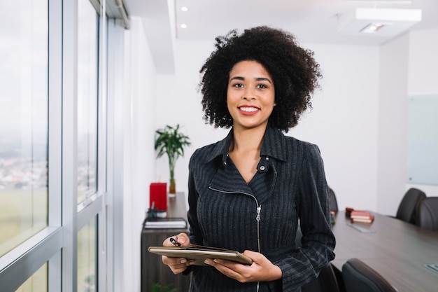 happy african american young lady with documents near window