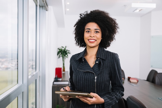 Happy African American young lady with documents near window