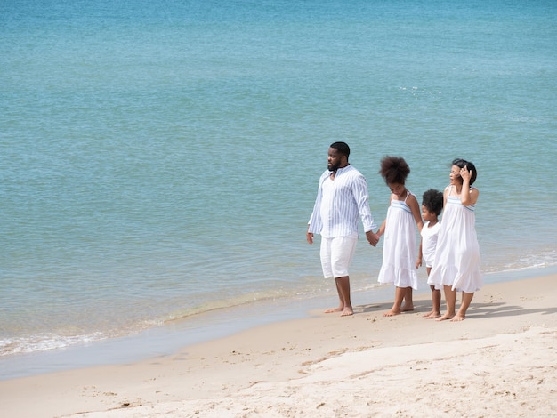 Happy African Asian family walking together at the beach on a beautiful day