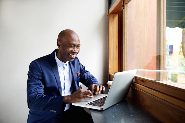 Happy african businessman working on laptop at cafe