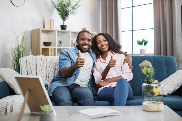 Happy african couple sitting on couch in embrace