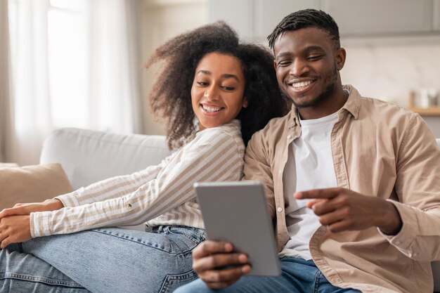 Photo happy african couple with digital tablet enjoys online content indoor