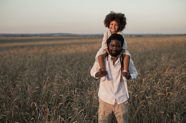 Foto padre e figlia africani felici in una passeggiata estiva in un campo