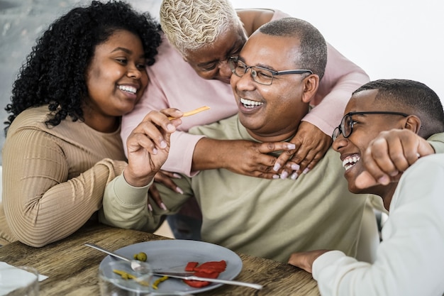 Happy african family eating lunch together at home - Main focus on boy face