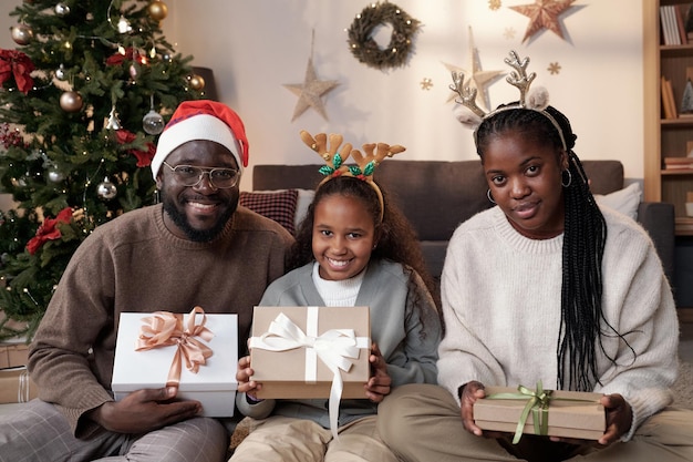 Happy African family of three holding Christmas presents