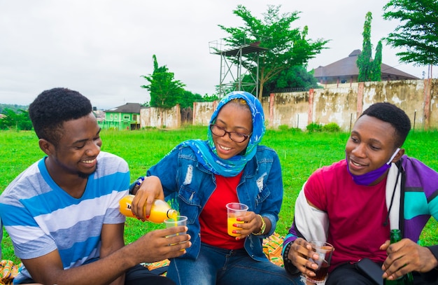 Happy african friends turning drink into their cup - friendship concept