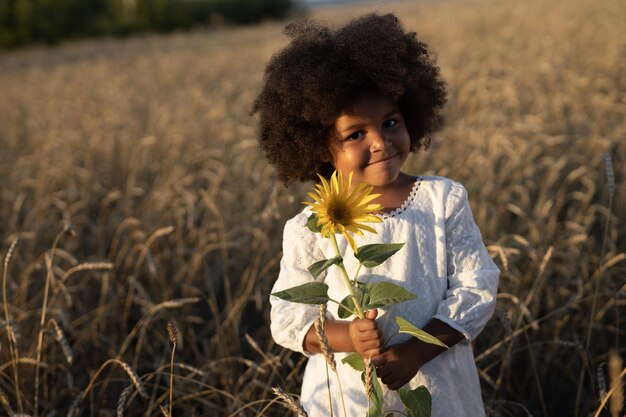 陽花と散歩している畑での毛を膨らませた幸せなアフリカの女の子